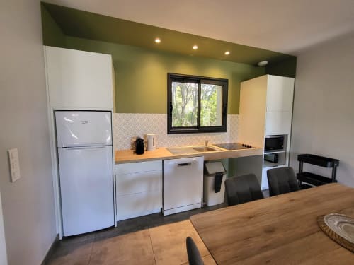 Modern kitchen with green accent wall, white appliances, wooden counter, and dining area at Villas Lantana, Lecci