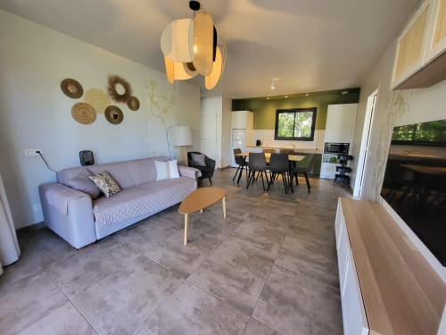 Modern open-plan living area at Villas Lantana in Lecci with purple sofa, wooden accents, and olive-toned kitchen