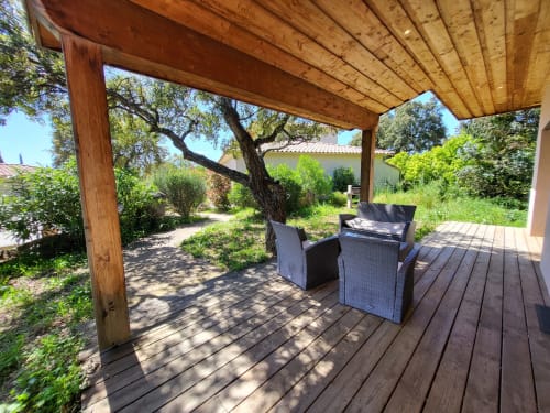 Wooden pergola seating area at Villas Lantana with rattan chairs and shade trees in Lecci