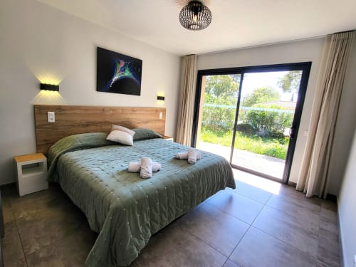 Modern bedroom at Villas Lantana Lecci with king bed, sliding doors to garden, and contemporary décor