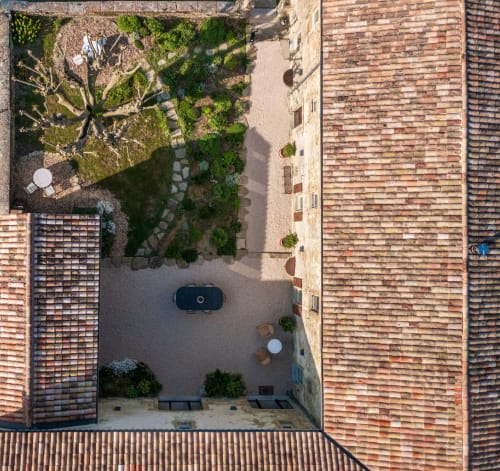 Vue aérienne de la cour L'Amiradou à Félines-sur-Rimandoule avec bâtiments en brique, jardin aménagé et voiture garée