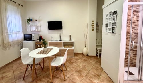 Moderno salón de apartamento en Baiona con comedor, televisor, cocineta y decoración contemporánea