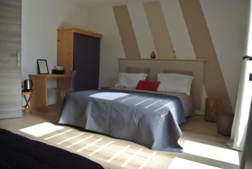 Chambre mansardée lumineuse à l'Hôtel CARPE DIEM à Lorgues avec plafonds inclinés, bureau en bois et lit confortable aux draps gris.