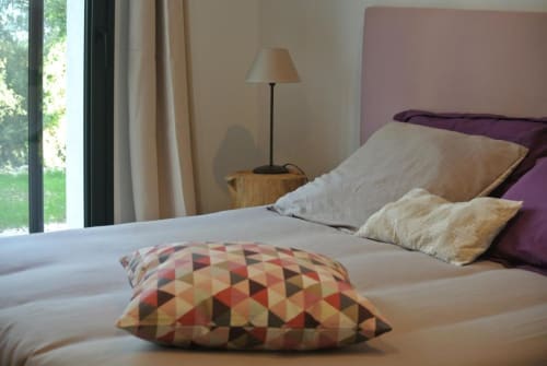 Chambre moderne à la Résidence Hôtelière CARPE DIEM à Lorgues avec tête de lit violette, coussins géométriques et vue sur le jardin