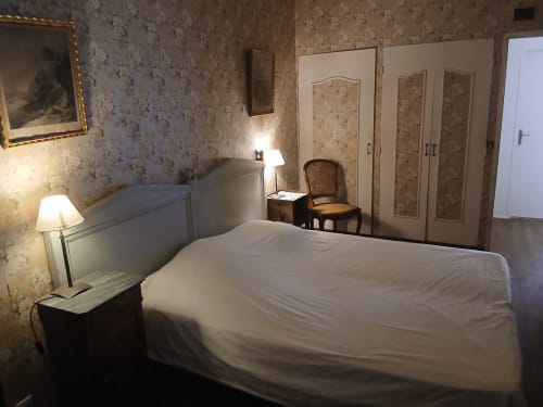 Chambre de la maison d'hôtes Domaine de Lamartine à Pont-Saint-Esprit avec papier peint fleuri et literie blanche