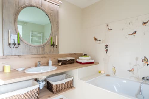 Modern bathroom at L'Amiradou B&B in Félines-sur-Rimandoule with round mirror, wooden countertop, bird-themed wall decals,