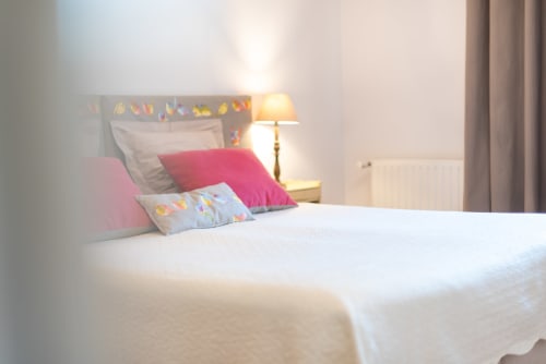 Cozy bedroom at L'Amiradou B&B in Félines-sur-Rimandoule with pink pillows, patterned headboard, and warm bedside lamp