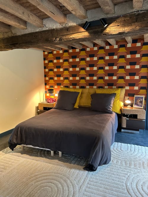 Chambre accueillante à Domaine de Blanvatel avec poutres apparentes, tête de lit géométrique colorée et décor rustique moderne