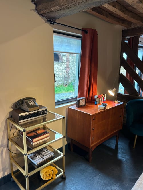 Chambre rustique du Domaine de Blanvatel avec poutres apparentes, bureau vintage, mobilier en bois et vue sur le jardin