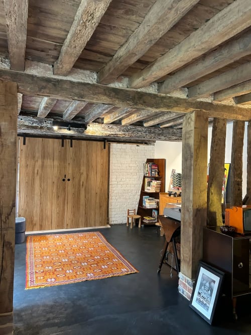 Espace loft rustique au Domaine de Blanvatel B&B à Saint-Pierre-en-Auge avec poutres apparentes, sol foncé et touches d'orange