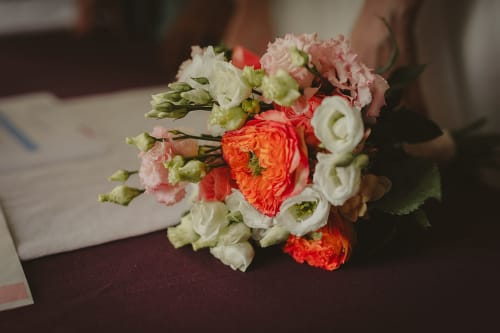 Bouquet de mariée éclatant avec roses corail et œillets blancs au Château de Baylac, Bugnein