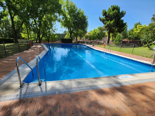 Piscina olímpica con terraza de madera y escaleras metálicas en el alojamiento rural Fuente Vieja, Arbancón, España