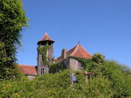 Château de Baylac, demeure historique française aux tours de toit en terre cuite, entourée de lierre verdoyant à Bugnein