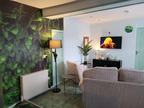 Modern apartment living room at Jane's B&B Guisborough with tropical leaf wallpaper, grey sofa, TV, and plant decor