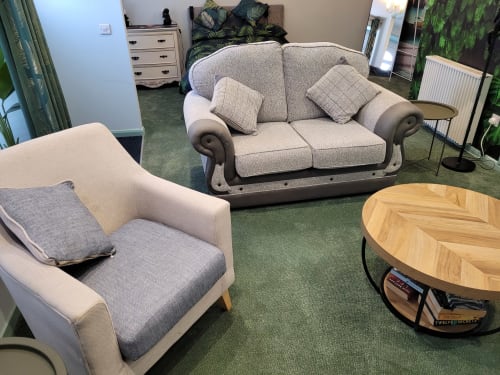 Spacious sitting area in Jane's B&B Guisborough apartment with beige sofa, armchair, wooden table, and green carpeting