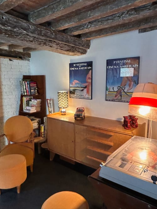 Salle cinéma rétro au Domaine de Blanvatel avec poutres apparentes, affiches vintage, mobilier en bois et ambiance chaleureuse