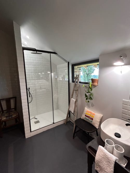 Salle de bain moderne à Domaine de Blanvatel avec douche à l'italienne, lavabo blanc et lumière naturelle