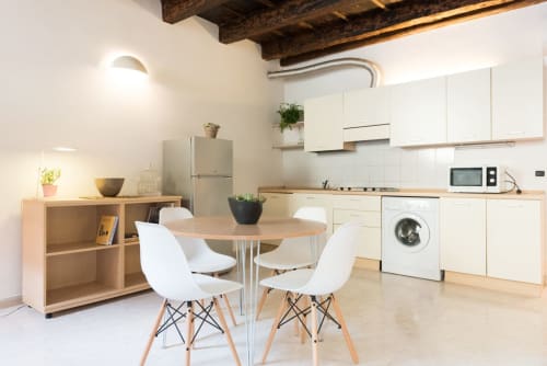 Zona living-cucina moderna dell'appartamento Le Arche a Verona con tavolo da pranzo, mobili bianchi e travi in legno