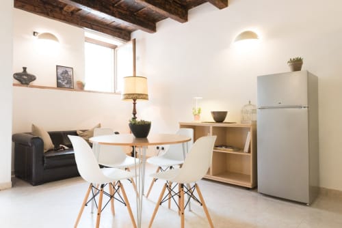 Moderno appartamento alle Arche Verona con tavolo da pranzo, sedie bianche, divano nero, angolo cucina e travi in legno