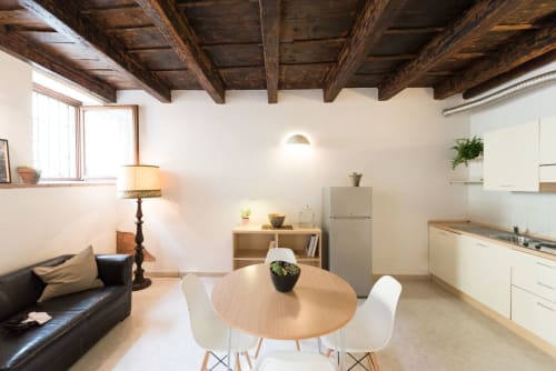 Moderno monolocale a Verona con travi in legno a vista, cucina aperta, zona pranzo, divano in pelle e vista sulla città