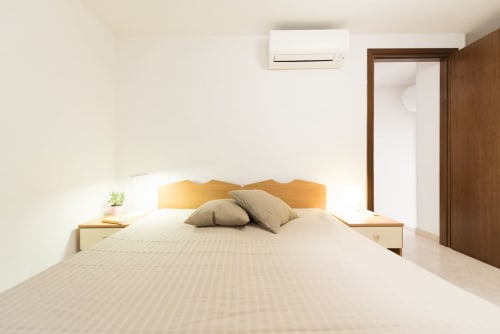 Camera da letto moderna presso l'aparthotel Le Arche a Verona con letto in legno, biancheria neutra e climatizzazione