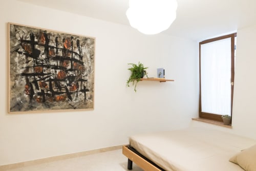 Camera da letto minimal a Verona con letto, opera d'arte astratta, scaffale in legno con pianta, finestra e lampada moderna al soffitto