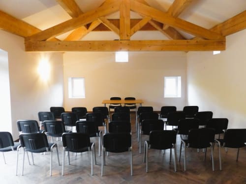 Modern meeting room at L'Amiradou B&B in Félines-sur-Rimandoule with exposed wooden beams, black chairs, and natural light.