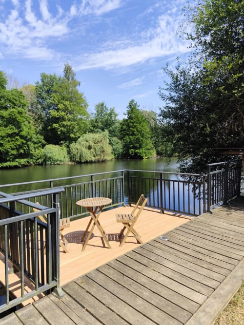 Terrasse au bord de la rivière du gîte Accolade à Châteaudun avec mobilier offrant une vue sur la rivière et les arbres