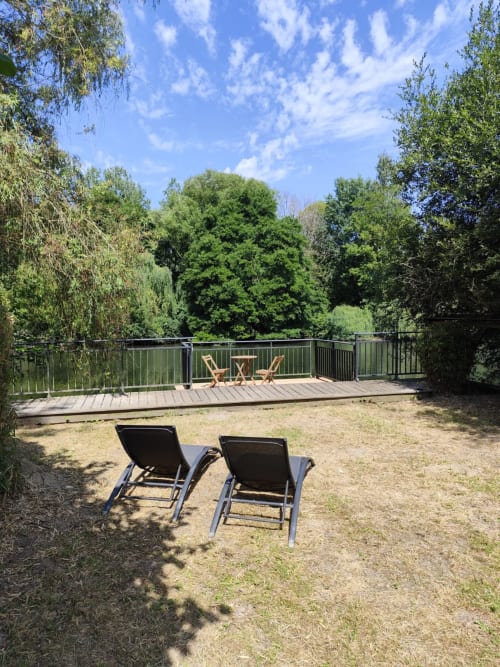 Jardin en bord de rivière avec transats et terrasse en bois au gîte Accolade à Châteaudun
