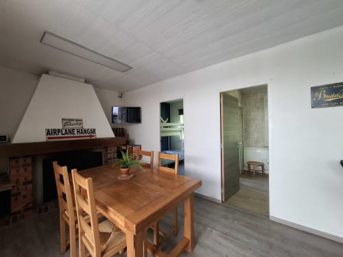 Salle à manger rustique à l'Accolade à Châteaudun avec table en bois, cheminée et enseigne vintage de hangar aérien