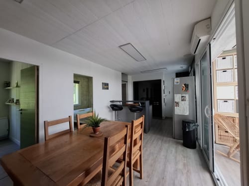 Salle à manger du cottage Accolade à Châteaudun avec table en bois, cuisine et accès à la vue sur la rivière