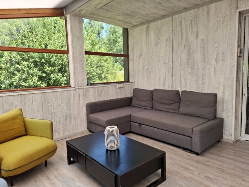 Salon moderne de la Accolade avec canapé gris, fauteuil jaune, table noire et vue sur la rivière à Châteaudun