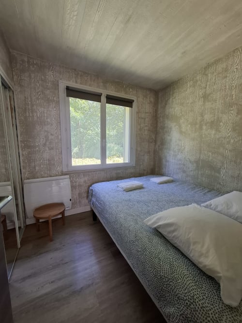 Chambre cosy du Château Accolade avec lits doubles, plafond en bois et vue sur la rivière