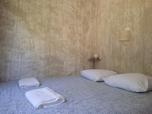 Chambre minimaliste à Accolade Châteaudun avec oreillers blancs, linge plié, papier peint effet bois et vue sur la rivière