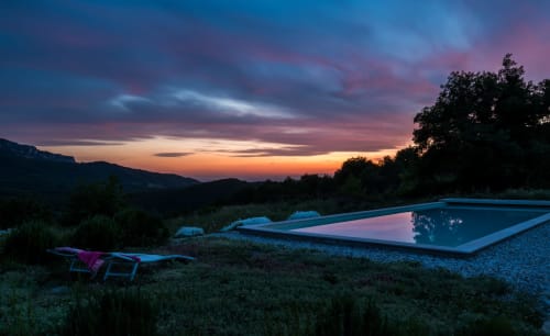 L' Amiradou's infinity pool at dusk overlooking Félines-sur-Rimandoule with dramatic sunset sky and mountains.