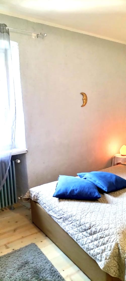 Camera accogliente a CasaRosada, resort benessere a Vidrazzo, con cuscini blu, decorazione lunare dorata e vista sul giardino