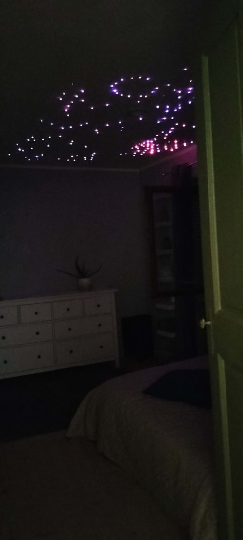 Bedroom at CasaRosada in Vidracco with glowing purple LED lights on ceiling creating starry ambiance above bed