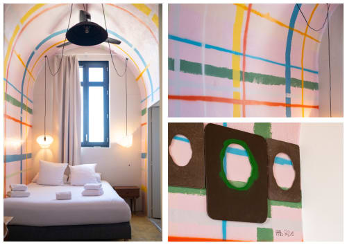 Chambre moderne colorée à l'Hôtel La Prison à Béziers avec art mural géométrique, suspension et détail de plafond voûté.