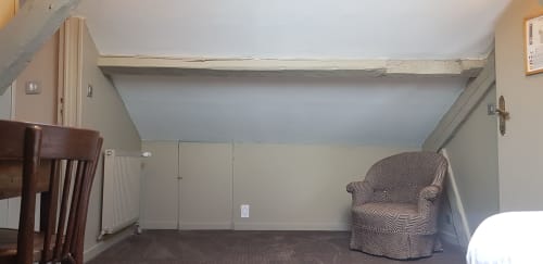 Chambre mansardée de l'hôtel Les Cabines à Houlgate avec plafond en pente, fauteuil, radiateur et parquet
