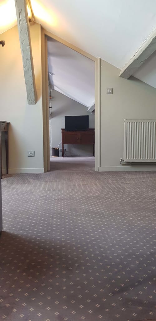 Suite avec vue mer à l'hôtel Les Cabines à Houlgate, porte ouverte, sol moquetté, radiateur et téléviseur visible dans la pièce adjacente