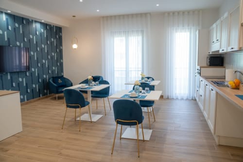 Zona living e cucina moderna open-plan presso il Ruah Pompei B&B a Pompei, con sedie blu, tavoli bianchi e