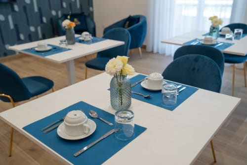 Elegante sala da pranzo del Ruah Pompei B&B a Pompei con tovagliette blu, stoviglie bianche e fiori gialli