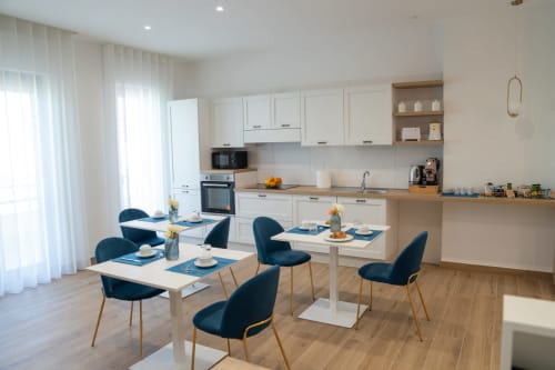 Cucina e sala da pranzo open-plan moderna presso Ruah Pompei B&B a Pompei con mobili bianchi, bancone in legno e tavolo blu