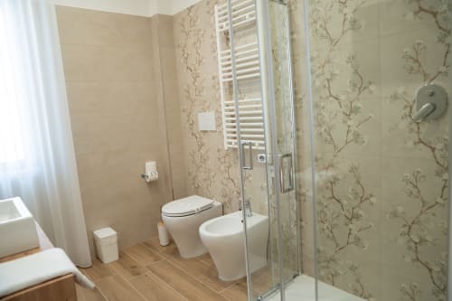 Modern bathroom at Ruah Pompei in Pompeii with toilet, bidet, walk-in shower, and floral wallpaper