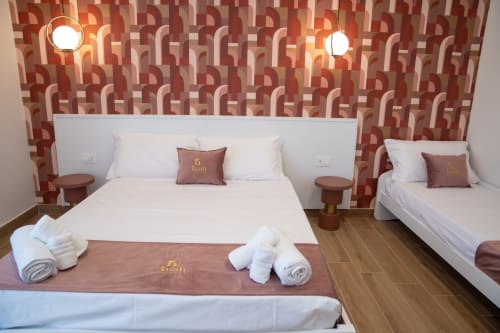 Triple room at Ruah Pompei B&B in Pompeii with geometric wallpaper, two beds, white bedding, and brown accent pillows