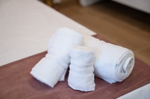 Rolled white towels displayed on burgundy towel at Ruah Pompei bed and breakfast in Pompei, Italy