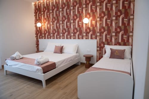Triple room at Ruah Pompei B&B in Pompeii with two white beds, red patterned wallpaper, and wooden flooring