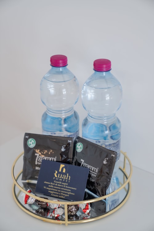 Cesto di benvenuto presso Ruah Pompei con bottiglie d'acqua, pacchetti di caffè e cioccolatini su vassoio dorato