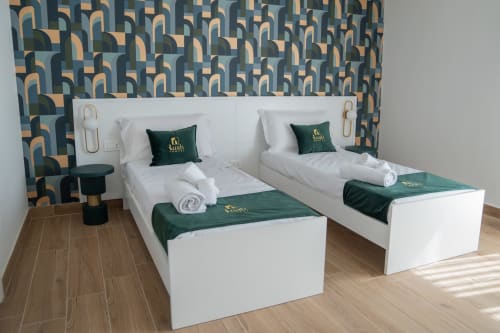 Two twin beds with white linens and green accents at Ruah Pompei hotel in Pompeii, featuring patterned wallpaper and modern