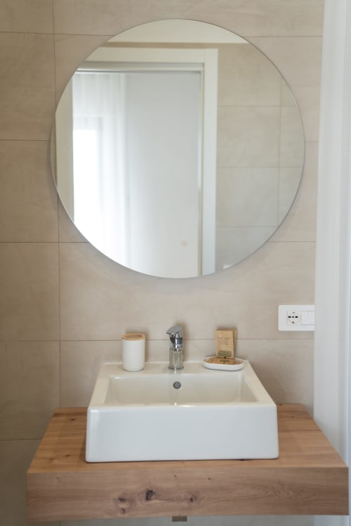 Modern bathroom sink with round mirror at Ruah Pompei B&B in Pompeii, Italy